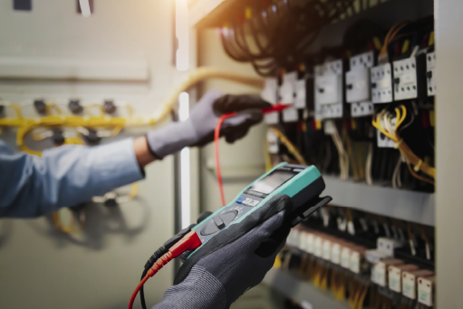Engineer hand holding AC multimeter checking electric current voltage at circuit breaker terminal