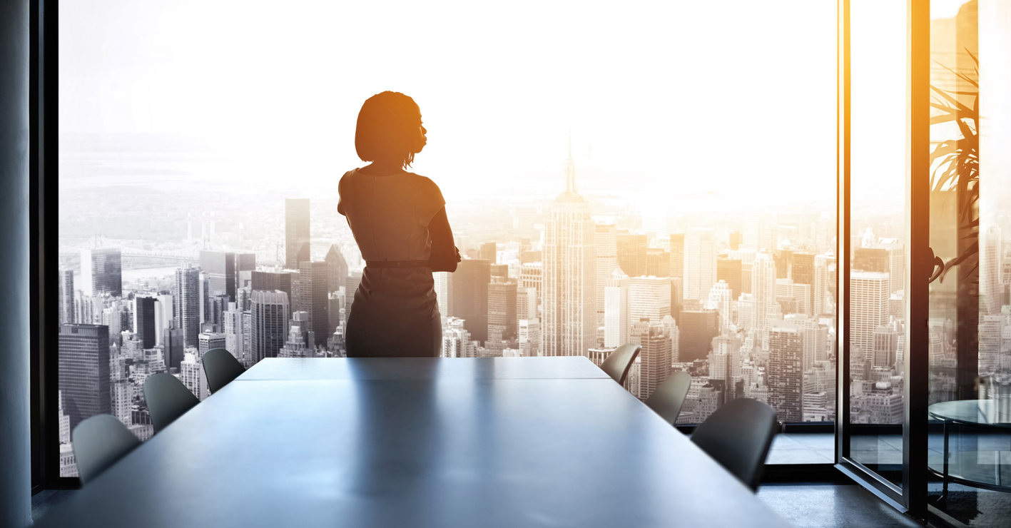 Rearview shot of a young businesswoman looking out from a large window in the office